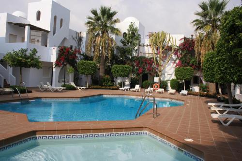 una piscina nel mezzo di un cortile con palme di Apartamentos Torrelaguna a Vera