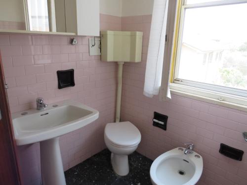 a pink bathroom with a toilet and a sink at La Baia di Lori in Pesaro