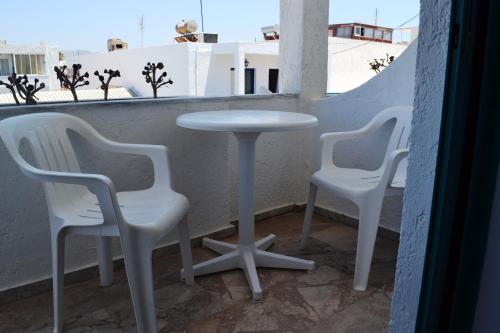 3 sillas blancas y una mesa en el balcón en HOTEL ARANT en Mastichari