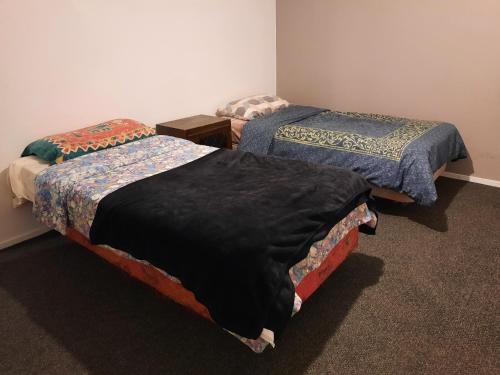 two beds sitting next to each other in a room at Papamoa Budget Accommodation in Papamoa