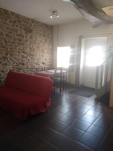 - un salon avec un canapé rouge et un mur en briques dans l'établissement Gite équestre en Normandie Haras de Sainte Colombe, à Sainte-Colombe