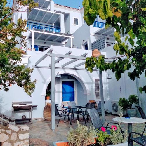 a white building with a patio with chairs and tables at 9 Muses in Agia Pelagia Kythira