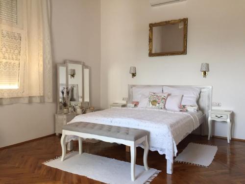 Dormitorio blanco con cama blanca y espejo en Bacchus Apartman - Borbarlang, Badacsony, en Badacsonytomaj