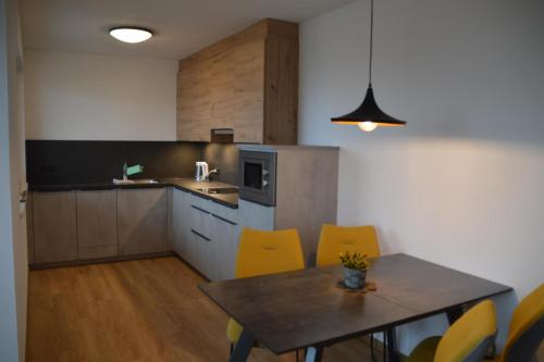 a kitchen with a table and yellow chairs at Apart Bergsonne in Fiss