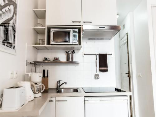 a white kitchen with a sink and a microwave at Montmartre Apartments Dalida in Paris