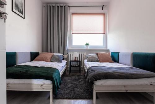 two beds in a room with a window at Quadratum Apartment by Renters in Gdańsk