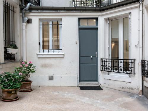 une porte bleue sur une maison blanche avec des plantes en pot dans l'établissement Montmartre Apartments Matisse, à Paris