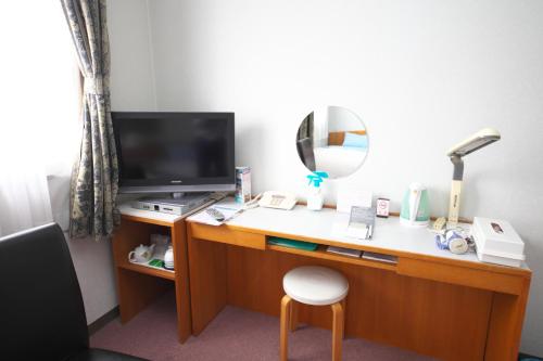 a room with a desk with a television and a mirror at 時津ヤスダオーシャンホテル in Togitsu