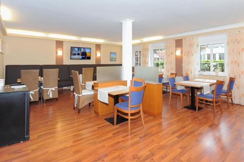 a restaurant with tables and chairs and a tv at Hotel Garni Benser Watt in Bensersiel