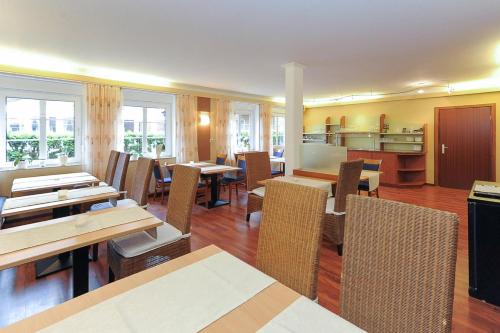 un restaurante con mesas y sillas de madera y ventanas en Hotel Garni Benser Watt, en Bensersiel