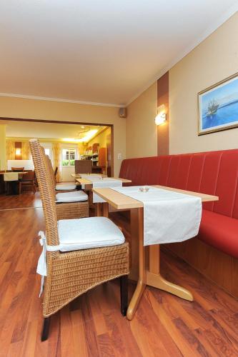a restaurant with tables and chairs and a red couch at Hotel Garni Benser Watt in Bensersiel