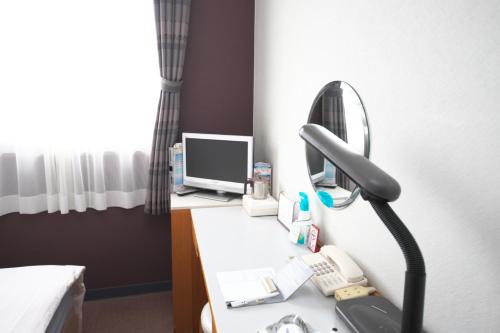 a room with a desk with a mirror and a phone at 時津ヤスダオーシャンホテル in Togitsu