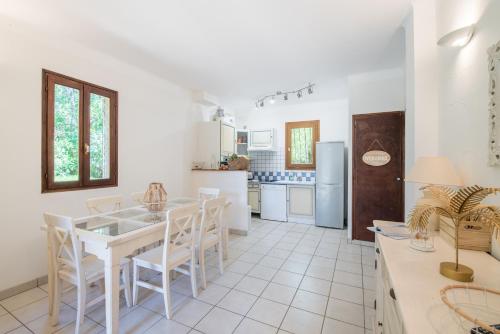 une cuisine blanche avec une table et des chaises blanches dans l'établissement La Pinède - Maison proche plages, à Pietrosella