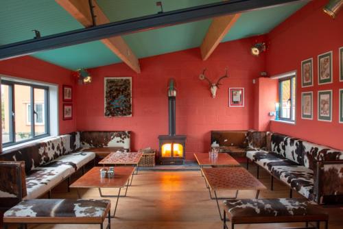 a room with red walls and couches and a fireplace at 1 Bed Shepherds Hut - Sleeps 2 -Wood Fired Hot Tub in Charlton Musgrove