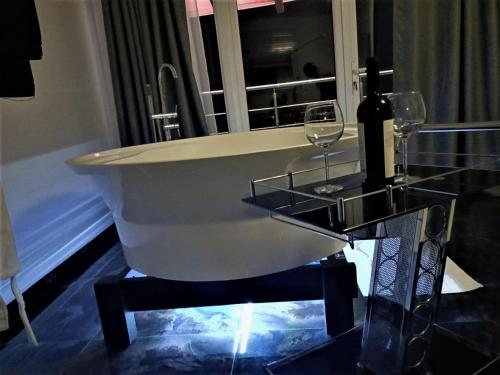a bath tub with two wine glasses and a mirror at Cazare Casa Noastra in Viforîta