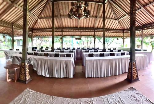 a large banquet hall with white tables and chairs at Kampoeng Wisata Rumah Joglo in Bogor
