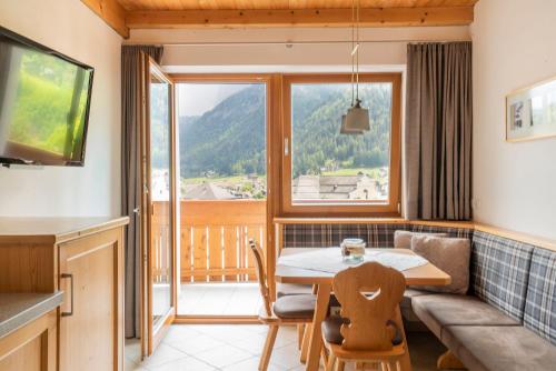 a kitchen and dining room with a table and a window at Apartments Ansciuda in Ortisei