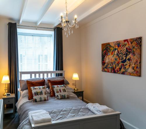 a bedroom with a bed with a painting on the wall at The Old Paint Shop Apartment - Centrally Situated in Anstruther