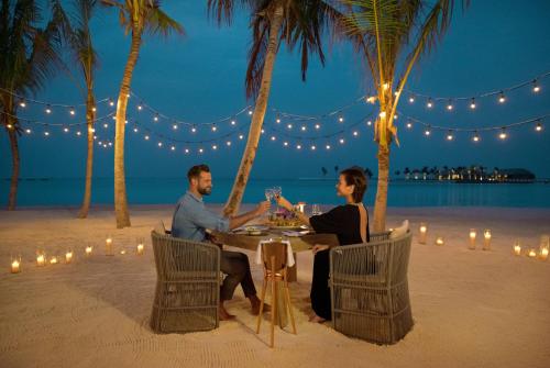 a man and a woman sitting at a picnic table at Kuda Villingili Resort Maldives in North Male Atoll