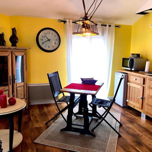 a kitchen with a table and chairs and a clock on the wall at LE DUPE in Brissac-Quincé
