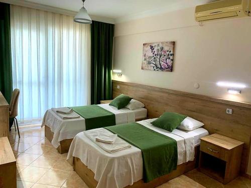 a hotel room with two beds with green sheets at Melodi Club Apart in Davutlar