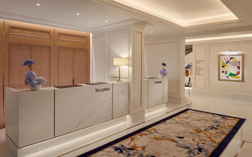 a large room with a lobby with a counter and a rug at Jumeirah Carlton Tower London in London