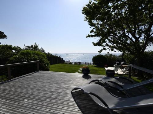 una terraza de madera con sillas y vistas al océano en Villa De La Plage en Pyla-sur-Mer