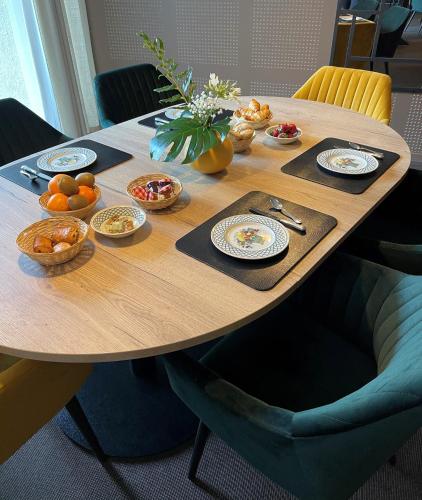 a wooden table with plates and bowls of food on it at Le Regina Hôtel restaurant in Hardelot-Plage
