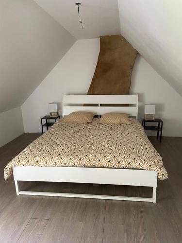 - un lit blanc dans une chambre blanche avec deux tables dans l'établissement La Bassurelle, à Saint-Valery-sur-Somme