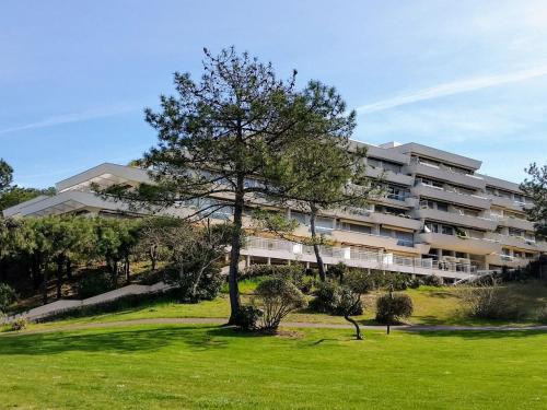 een groot appartementencomplex met een boom in een veld bij Appartement Panoramic in Arcachon