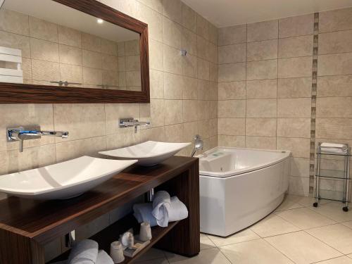 a bathroom with two sinks and a tub and a bath tub at Best Western Premier Le Patio des Artistes Wellness Jacuzzi in Cannes