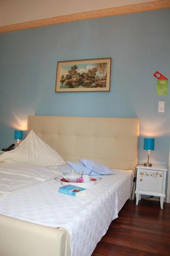 a bedroom with a white bed with a picture on the wall at Hotel Waldfriede in Darmstadt