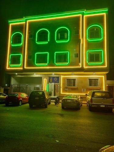 ein Neonschild vor einem Gebäude mit geparkten Autos in der Unterkunft ريـــــم للشقق المفروشة والأجنحــة الفـندقيـة Reem Hotel in Khobar
