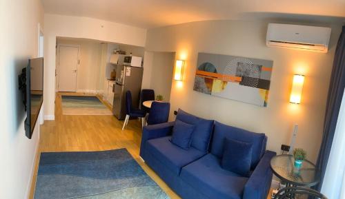 ein Wohnzimmer mit einem blauen Sofa und einer Küche in der Unterkunft Orbi city Luxury suit in Batumi