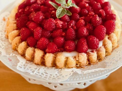 a cake with raspberries on top on a white plate at Grand Colonial Bed and Breakfast in Herkimer