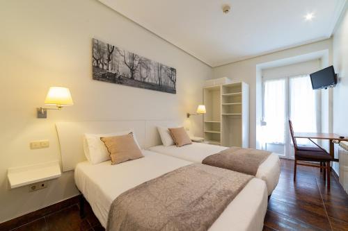a hotel room with two beds and a tv at Pension Aida in Donostia-San Sebastián
