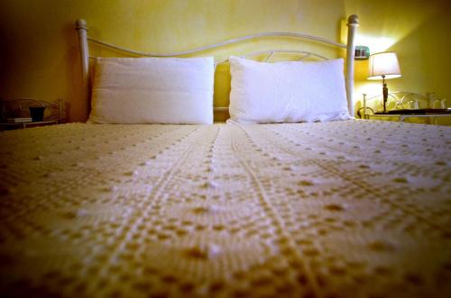 a bedroom with a white bed with two pillows at Casa De Ajala - B&B de Charme in Antica Dimora totalmente ristrutturata e dotata di tutti i confort Bagni privati Spazio living Patio esterno Ambienti climatizzati Degustazioni prodotti locali in Làconi