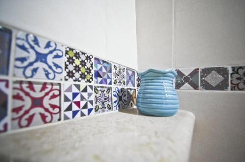 a blue vase sitting on a ledge in a room with tiles at Casa De Ajala - B&B de Charme in Antica Dimora totalmente ristrutturata e dotata di tutti i confort Bagni privati Spazio living Patio esterno Ambienti climatizzati Degustazioni prodotti locali in Làconi