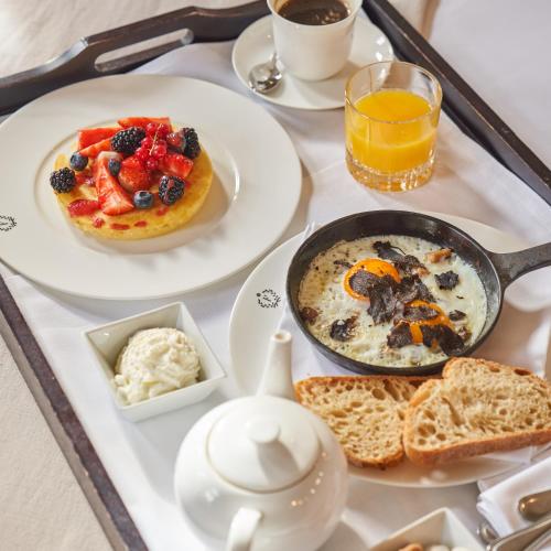 a breakfast tray with a breakfast of pancakes and fruit at The Franklin London - Starhotels Collezione in London