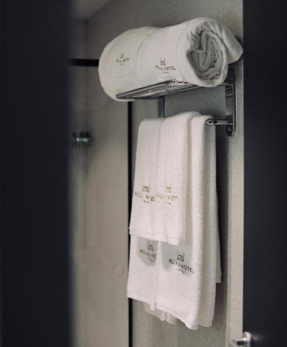 a towel rack with white towels in a bathroom at Mulaj Hotel in Tirana