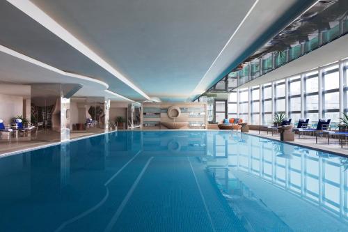 a large swimming pool with blue water in a building at Beijing Pudi Hotel in Beijing