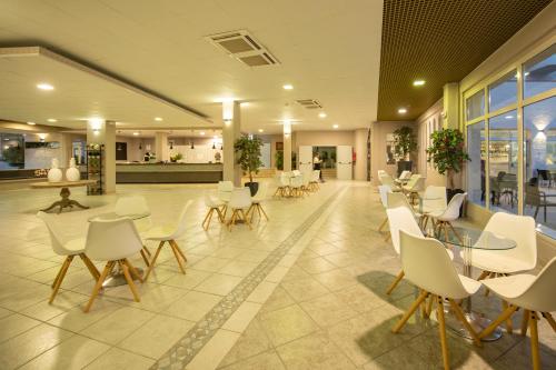 a lobby with white chairs and tables in a building at Hotel Club Eloro in Noto Marina