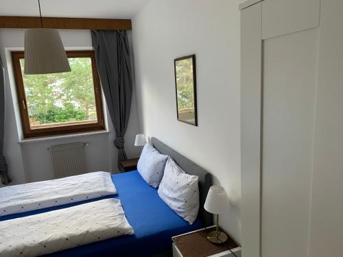 ein Schlafzimmer mit einem blauen Bett und einem Fenster in der Unterkunft Appartments Hilber in Bruneck