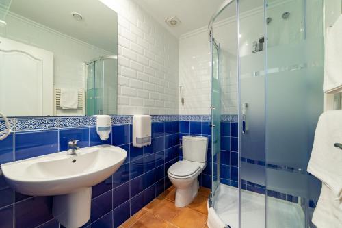 a blue tiled bathroom with a toilet and a sink at Pension Aida in Donostia-San Sebastián