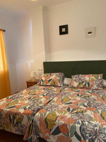 a bedroom with a bed with a colorful comforter at Apartahotel 4 vientos in Prado del Rey