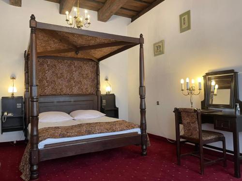 a bedroom with a canopy bed and a desk at Hotel Dwór Polski in Wrocław
