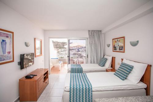 a hotel room with two beds and a balcony at Servatur Montebello in Puerto Rico de Gran Canaria
