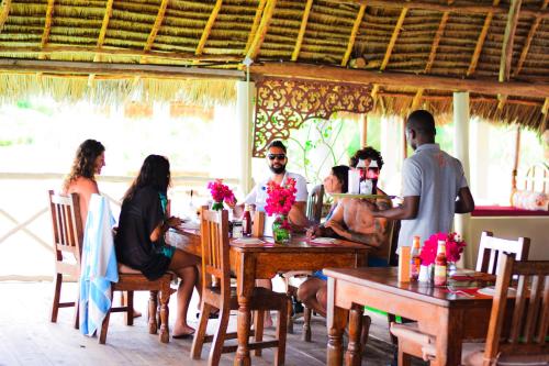 a group of people sitting at tables in a restaurant at Kikoi Boutique Hotel in Michamvi