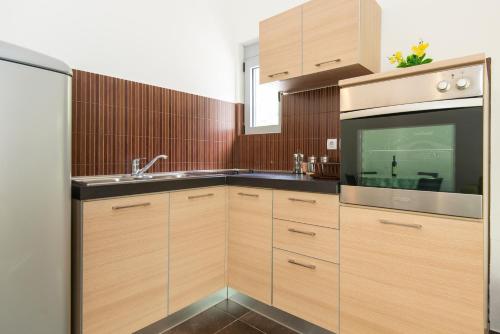 a kitchen with wooden cabinets and a sink and a microwave at Gemma di Cattaro Apartments in Kotor