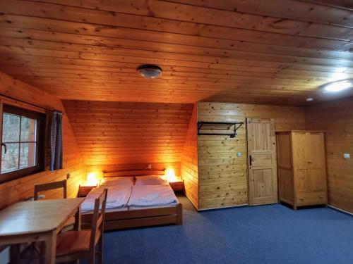 een slaapkamer in een houten hut met een bed en een tafel bij Apartmány Ski areal Kareš in Loučná nad Desnou